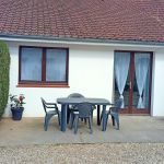Fa&ccedil;ade du g&icirc;te avec le coin terrasse &eacute;quip&eacute; d'un salon de jardin et d'un barbecue